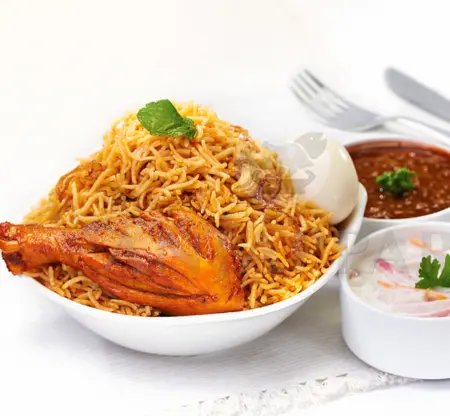 A bowl of chicken biryani with egg, a side of refreshing raitha, and a flavorful curry sauce