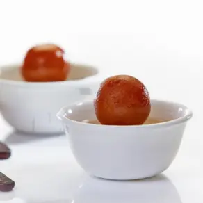 Two bowls brimming with delicious gulab jamun on a clean white surface inviting your taste buds