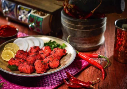 A plate of colorful delicous chilly chicken marinated with spices, served with lemon and onion.