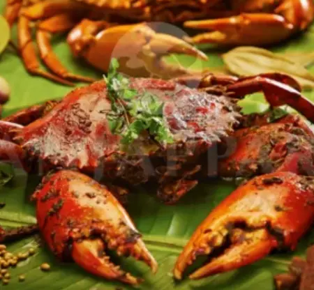 A whole crab served on a banana leaf garnished with mint leaves and other aromatic spices